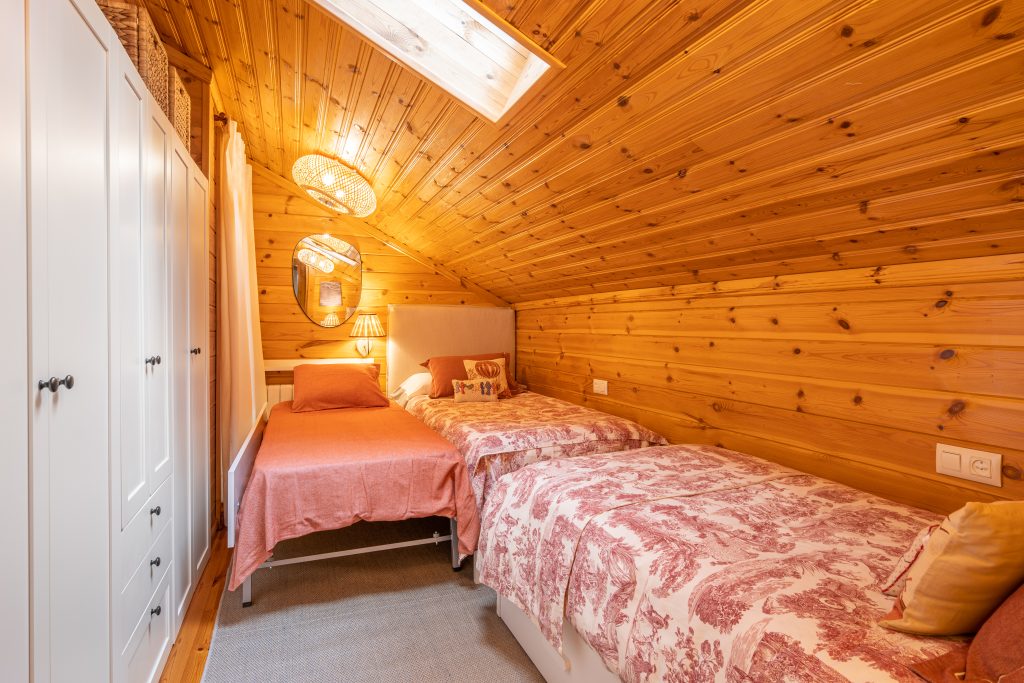 Cozy bedroom with three beds and white wardrobe in a modern cottage with wooden walls